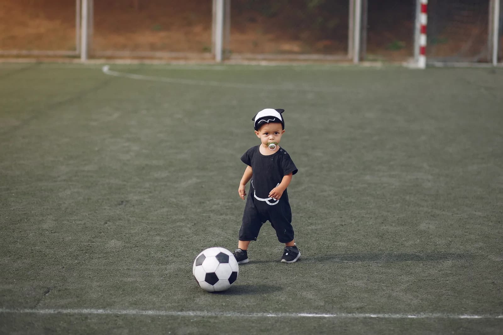 Liten gutt med fotball på en kunstgressbane